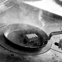 Meat being pan-fried on industrial hob